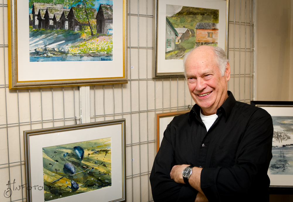 Kunstneren foran sine bilder i galleriet